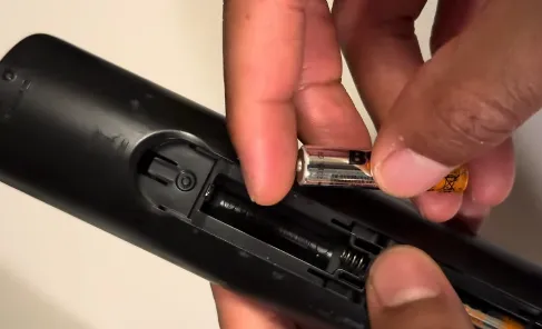 Person replacing batteries in TV remote.