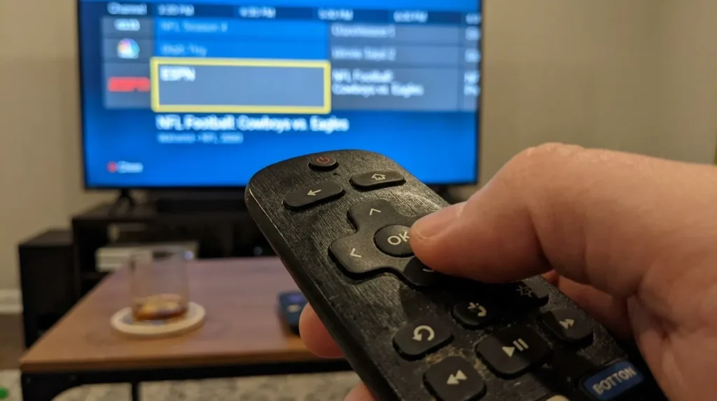 Hand using Spectrum TV remote to navigate to ESPN on channel guide